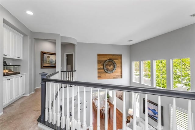corridor with light colored carpet, arched walkways, baseboards, an upstairs landing, and recessed lighting