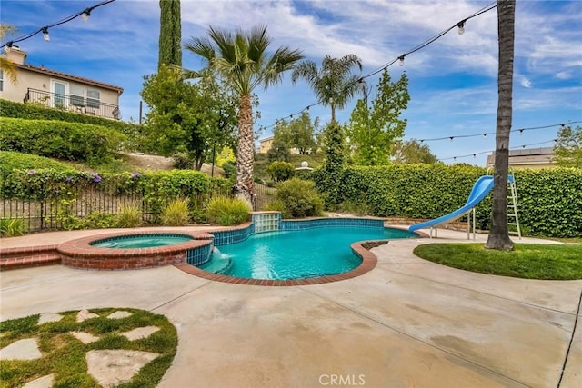 view of pool featuring fence, a water slide, a pool with connected hot tub, and a patio area