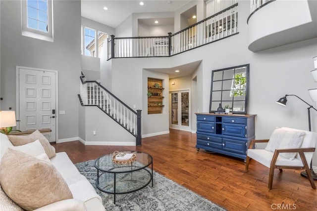 living room with baseboards, a high ceiling, wood finished floors, and stairway