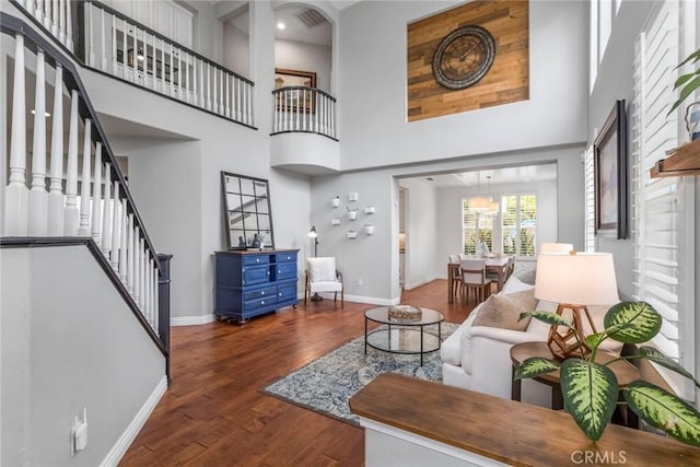 living area featuring dark wood-style flooring, baseboards, and a towering ceiling