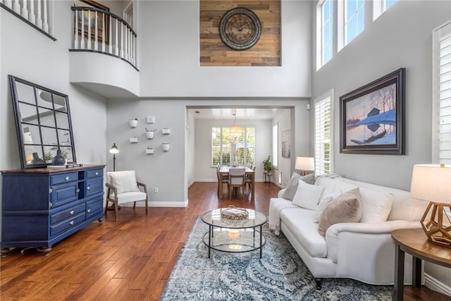 living area with wood-type flooring, a high ceiling, and baseboards