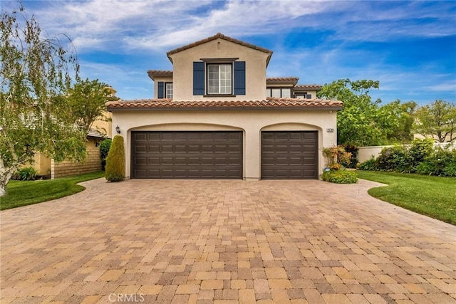 mediterranean / spanish home featuring a garage, stucco siding, a front yard, decorative driveway, and a tiled roof