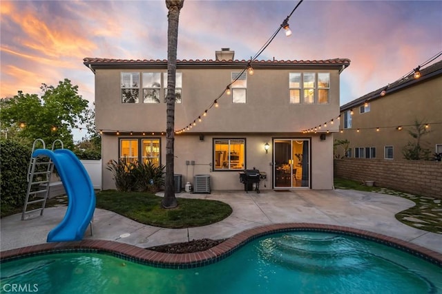 back of property featuring central AC, a chimney, a fenced backyard, and stucco siding