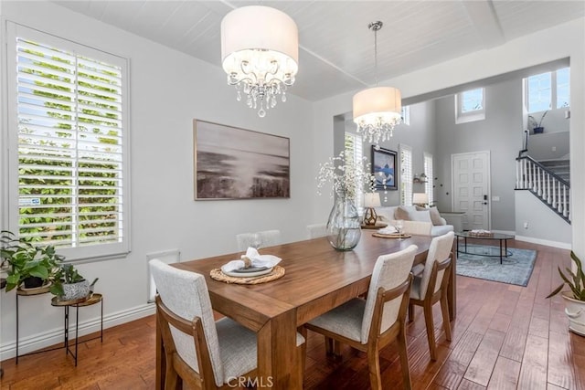 dining space with hardwood / wood-style flooring, an inviting chandelier, baseboards, and stairway