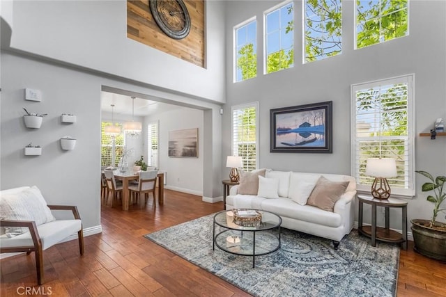 living area featuring wood-type flooring, baseboards, and a towering ceiling