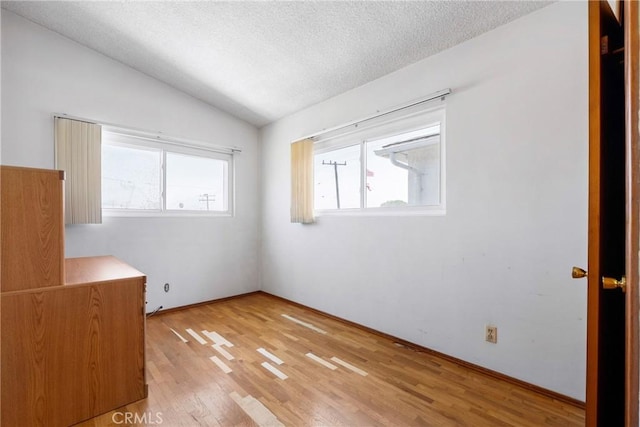 unfurnished bedroom featuring light wood-style flooring, a textured ceiling, and lofted ceiling