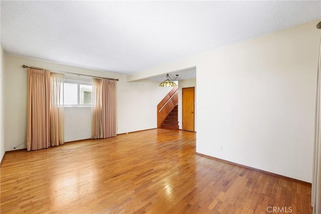 unfurnished room with stairs and light wood-style flooring