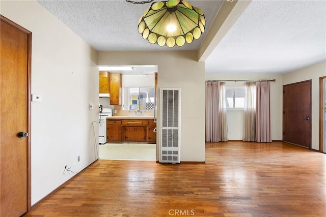 interior space with light wood-style floors, a heating unit, a textured ceiling, and baseboards