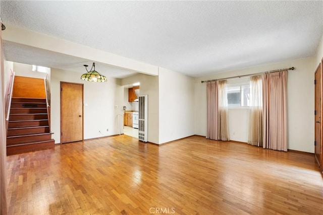unfurnished living room featuring stairway, a textured ceiling, and light wood-style flooring