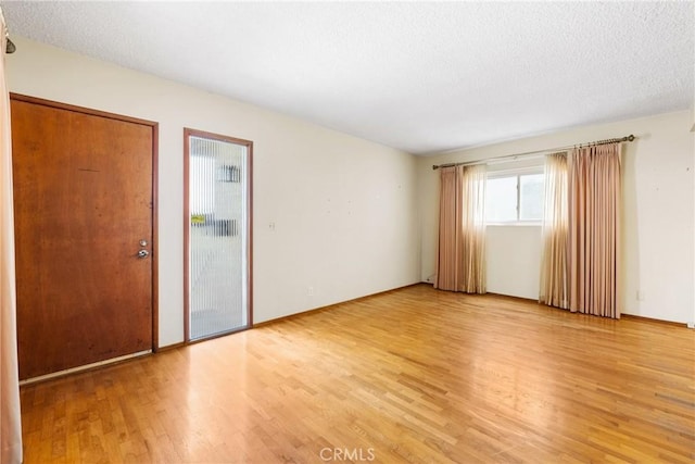 empty room with a textured ceiling and light wood finished floors