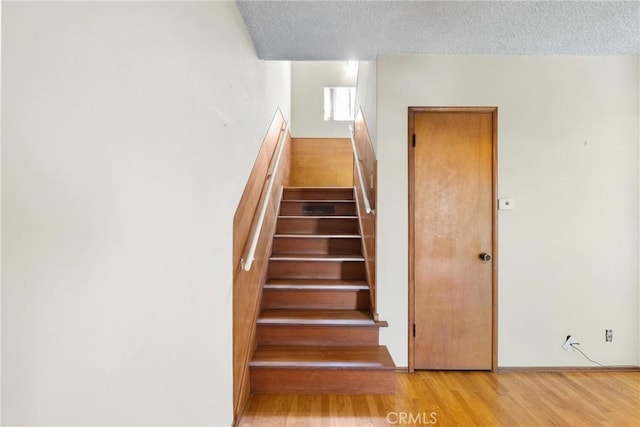 stairs featuring a textured ceiling and wood finished floors