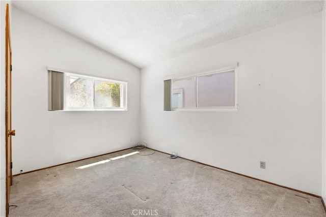 carpeted spare room featuring a textured ceiling and vaulted ceiling