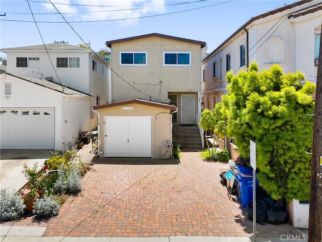 multi unit property with a garage, stucco siding, and decorative driveway