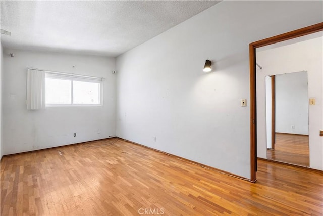 spare room with a textured ceiling and light wood-style flooring