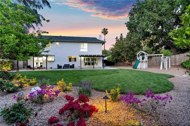 1061 Colby Cir, Thousand Oaks, CA 91362 - back of property at dusk featuring a playground, stucco siding, and a patio