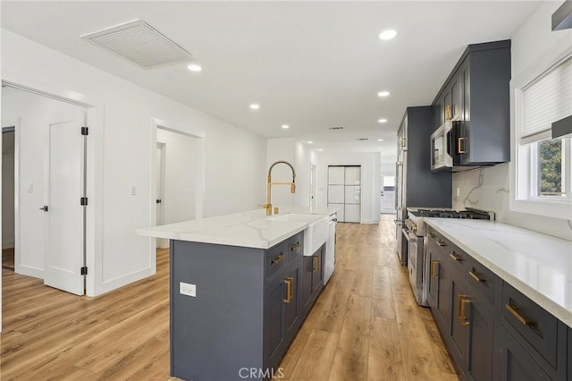 3427 S Victoria Ave, Los Angeles, CA 90016 - kitchen featuring visible vents, appliances with stainless steel finishes, a sink, light stone counters, and light wood-style floors