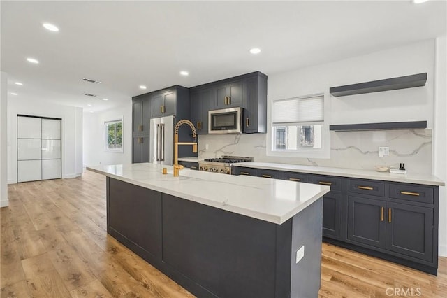 3427 S Victoria Ave, Los Angeles, CA 90016 - kitchen with visible vents, a kitchen island, light wood finished floors, backsplash, and stainless steel appliances