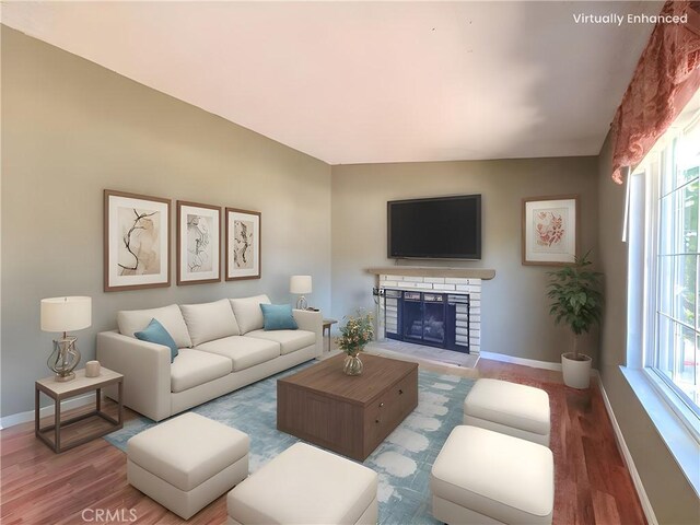 living room featuring baseboards, a fireplace with raised hearth, and wood finished floors