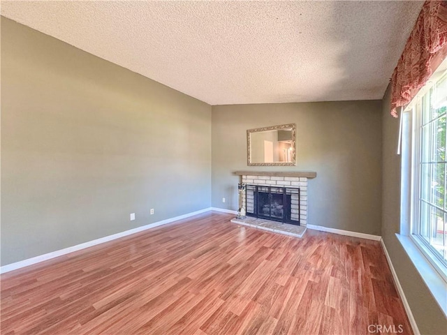 unfurnished living room with a textured ceiling, plenty of natural light, light wood finished floors, and a fireplace