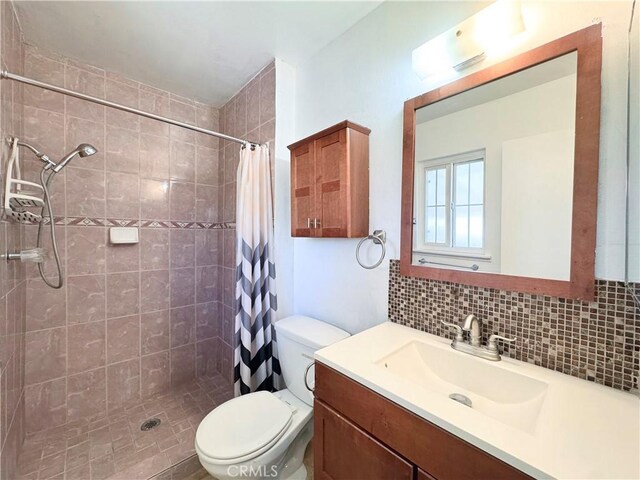 bathroom with vanity, decorative backsplash, toilet, and tiled shower