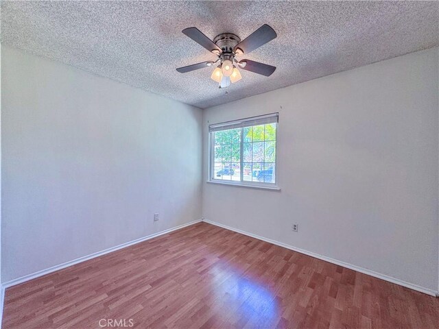 empty room featuring baseboards, a textured ceiling, ceiling fan, and wood finished floors
