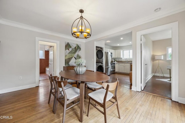 dining area with baseboards, stacked washing maching and dryer, a notable chandelier, and hardwood / wood-style floors