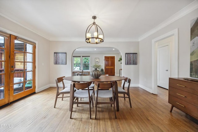 dining area with ornamental molding, light wood-style floors, baseboards, a chandelier, and arched walkways