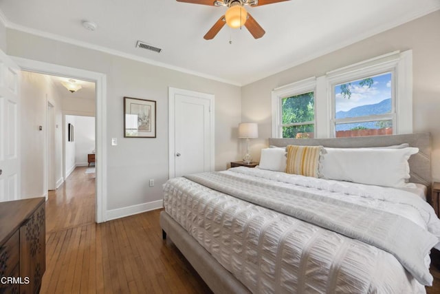 bedroom featuring crown molding, wood-type flooring, a ceiling fan, baseboards, and visible vents
