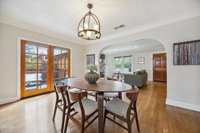 dining area featuring visible vents, baseboards, arched walkways, light wood finished floors, and a notable chandelier