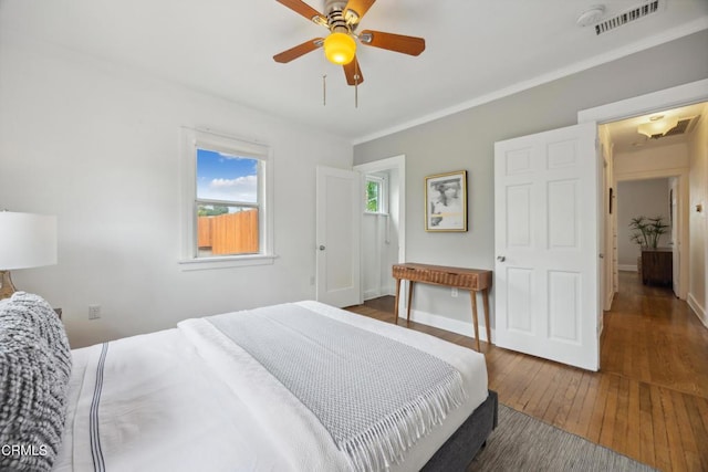 bedroom with visible vents, a ceiling fan, wood-type flooring, and baseboards