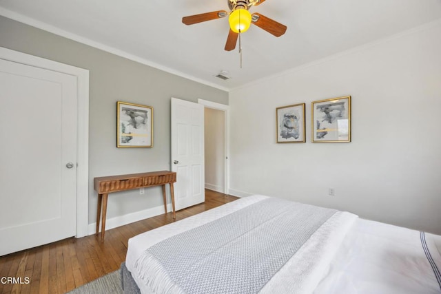 bedroom with wood-type flooring, a ceiling fan, baseboards, visible vents, and ornamental molding