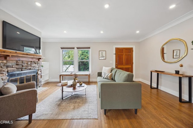 living area featuring a stone fireplace, baseboards, and wood finished floors