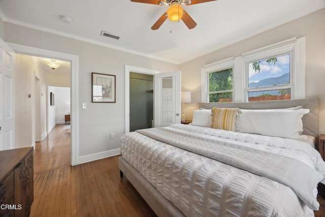 bedroom featuring wood-type flooring, baseboards, visible vents, ornamental molding, and a closet