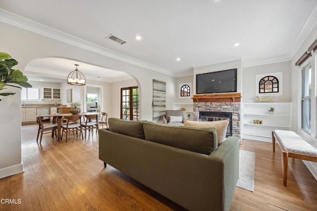 living area featuring arched walkways, plenty of natural light, and light wood-style floors