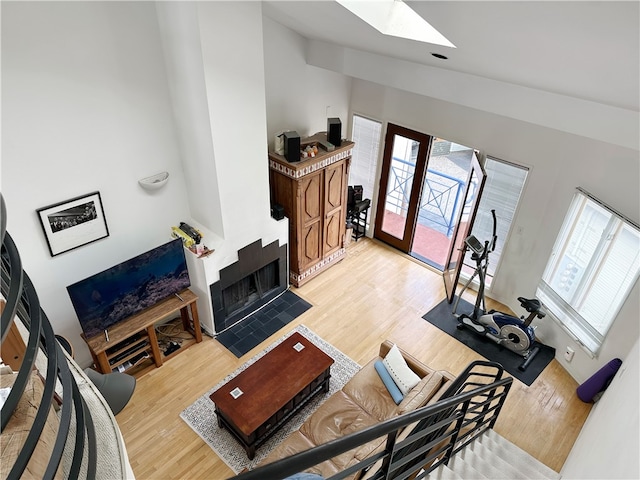 living room with light wood finished floors, vaulted ceiling with skylight, and a fireplace