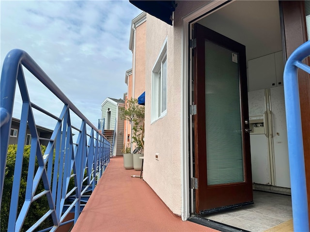 view of exterior entry featuring stucco siding and a balcony