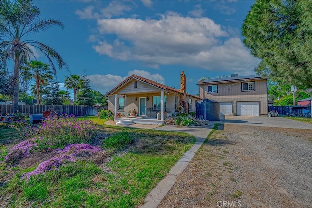 2415 E Childs Ave, Merced, CA 95341 - rear view of house featuring fence, an attached garage, a chimney, concrete driveway, and solar panels