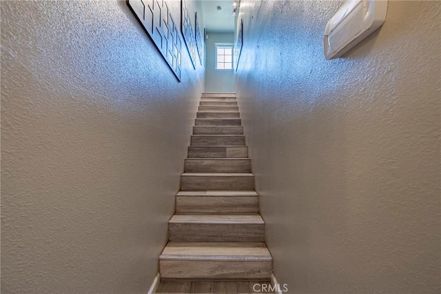 2415 E Childs Ave, Merced, CA 95341 - staircase featuring baseboards, a textured wall, an AC wall unit, and wood finished floors