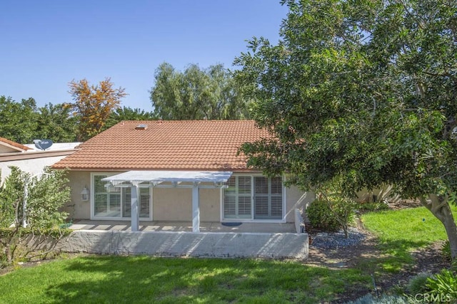 rear view of house featuring a pergola, stucco siding, a lawn, a patio, and a tiled roof