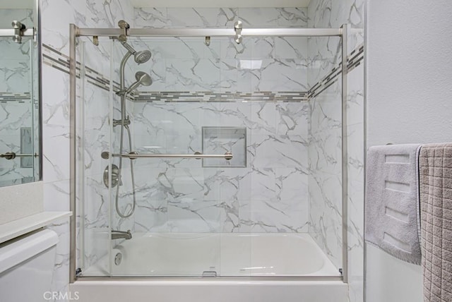 full bath featuring combined bath / shower with glass door and toilet