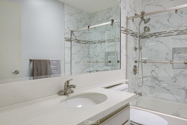 full bathroom featuring toilet, combined bath / shower with glass door, and vanity