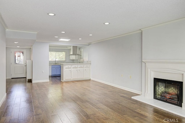 unfurnished living room with crown molding, recessed lighting, baseboards, and wood finished floors