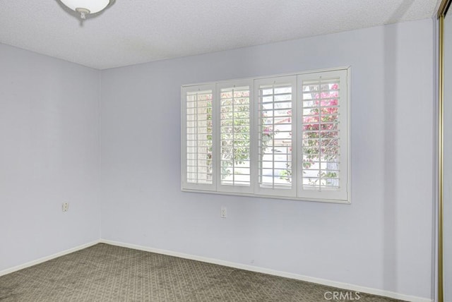 carpeted empty room with a textured ceiling and baseboards