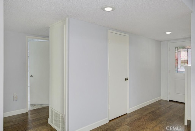 interior space with baseboards, a textured ceiling, and wood finished floors