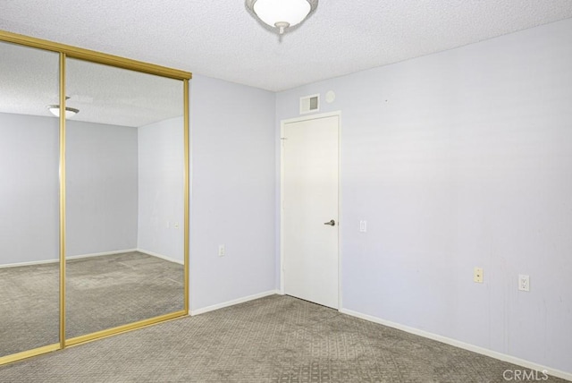 unfurnished bedroom featuring a closet, carpet flooring, a textured ceiling, and visible vents
