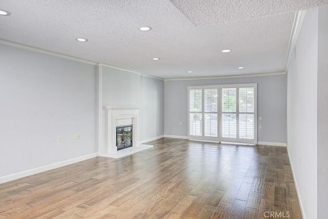 unfurnished living room featuring recessed lighting, ornamental molding, a textured ceiling, and wood finished floors