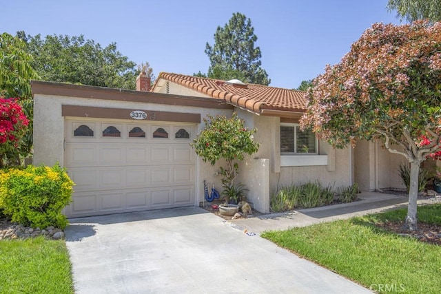 mediterranean / spanish-style home featuring stucco siding, a chimney, a tiled roof, concrete driveway, and an attached garage
