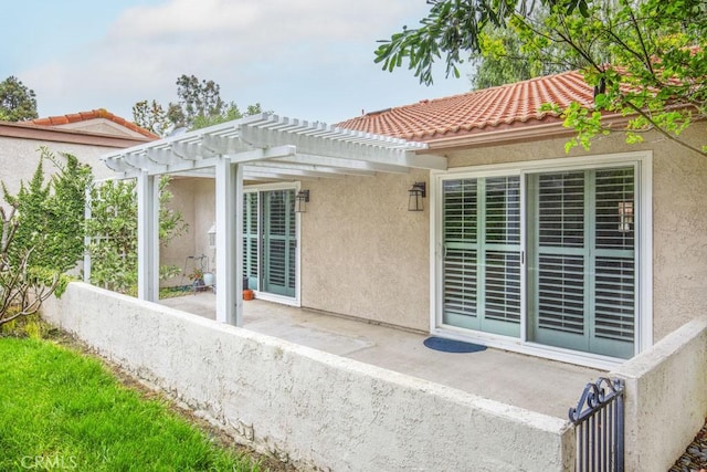 back of house with a pergola, stucco siding, and a tiled roof