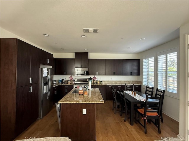 900 N Primrose Ln Unit A, Azusa, CA 91702 - kitchen featuring stainless steel appliances, light wood finished floors, an island with sink, light stone countertops, and dark brown cabinetry
