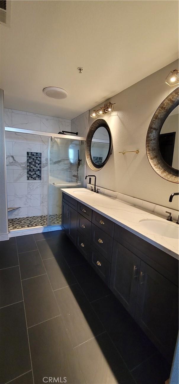 full bathroom featuring a sink, a shower stall, double vanity, and visible vents